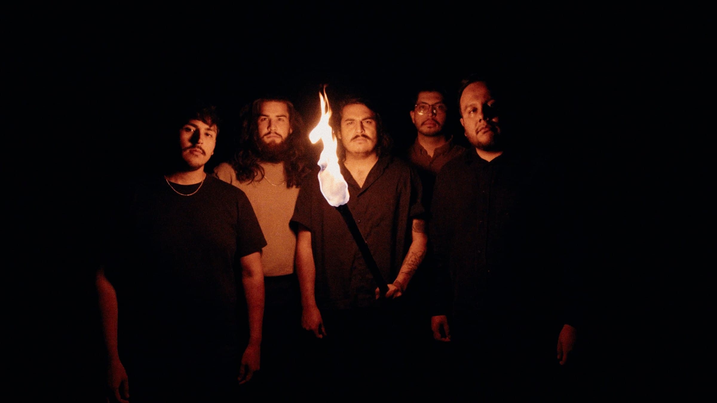 Bloodlines 2026 promo — the five members in the dark behind a lit torch